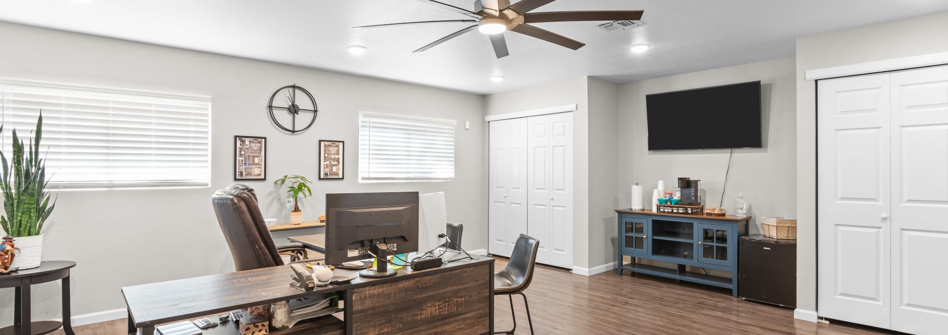a home office with a ceiling fan and hardwood floors at The Calypso Apartments