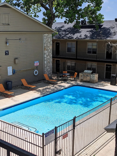 a pool in front of a building with a patio at The Calypso Apartments