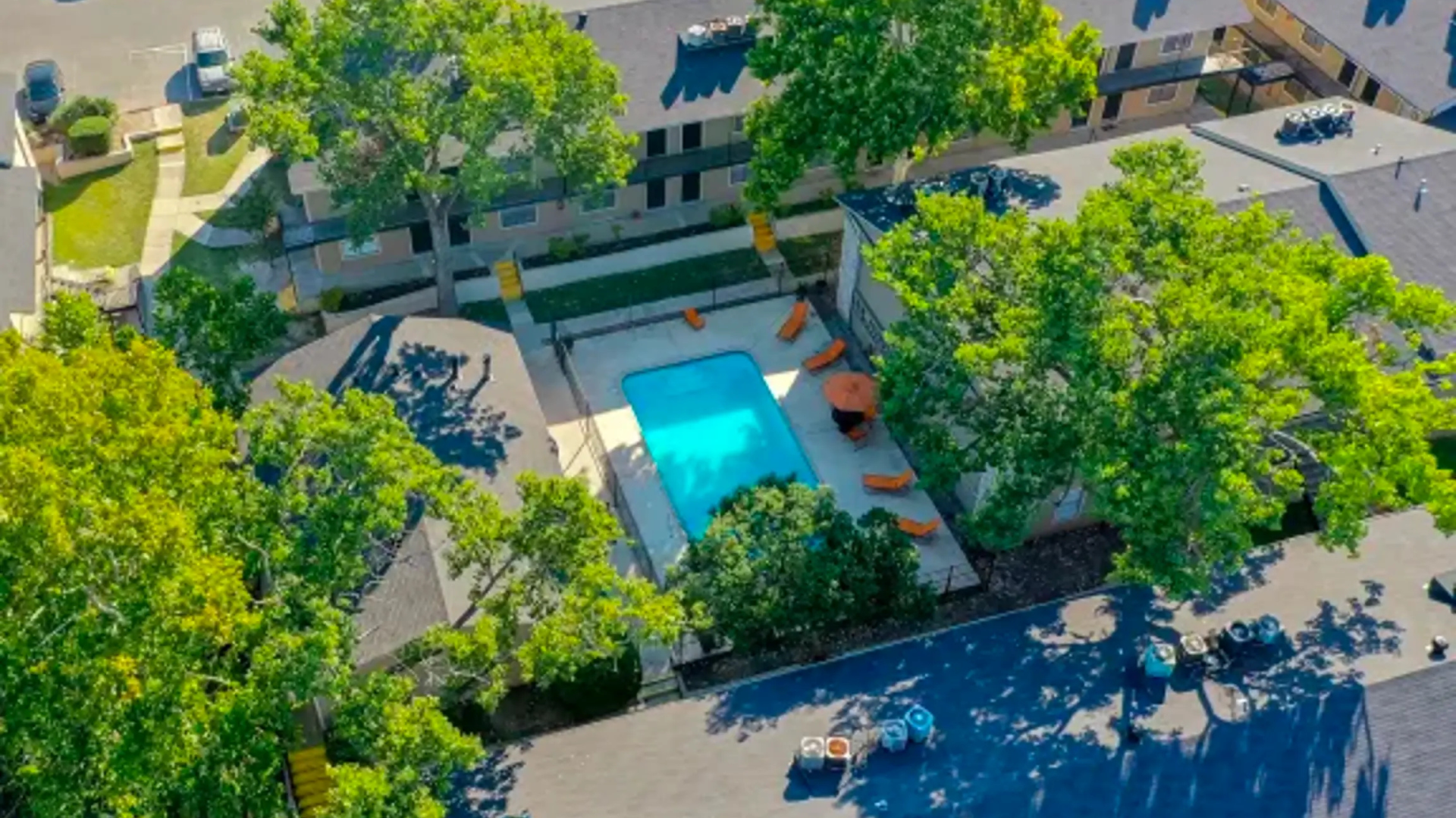 an aerial view of a pool and trees in a residential area at The Calypso Apartments